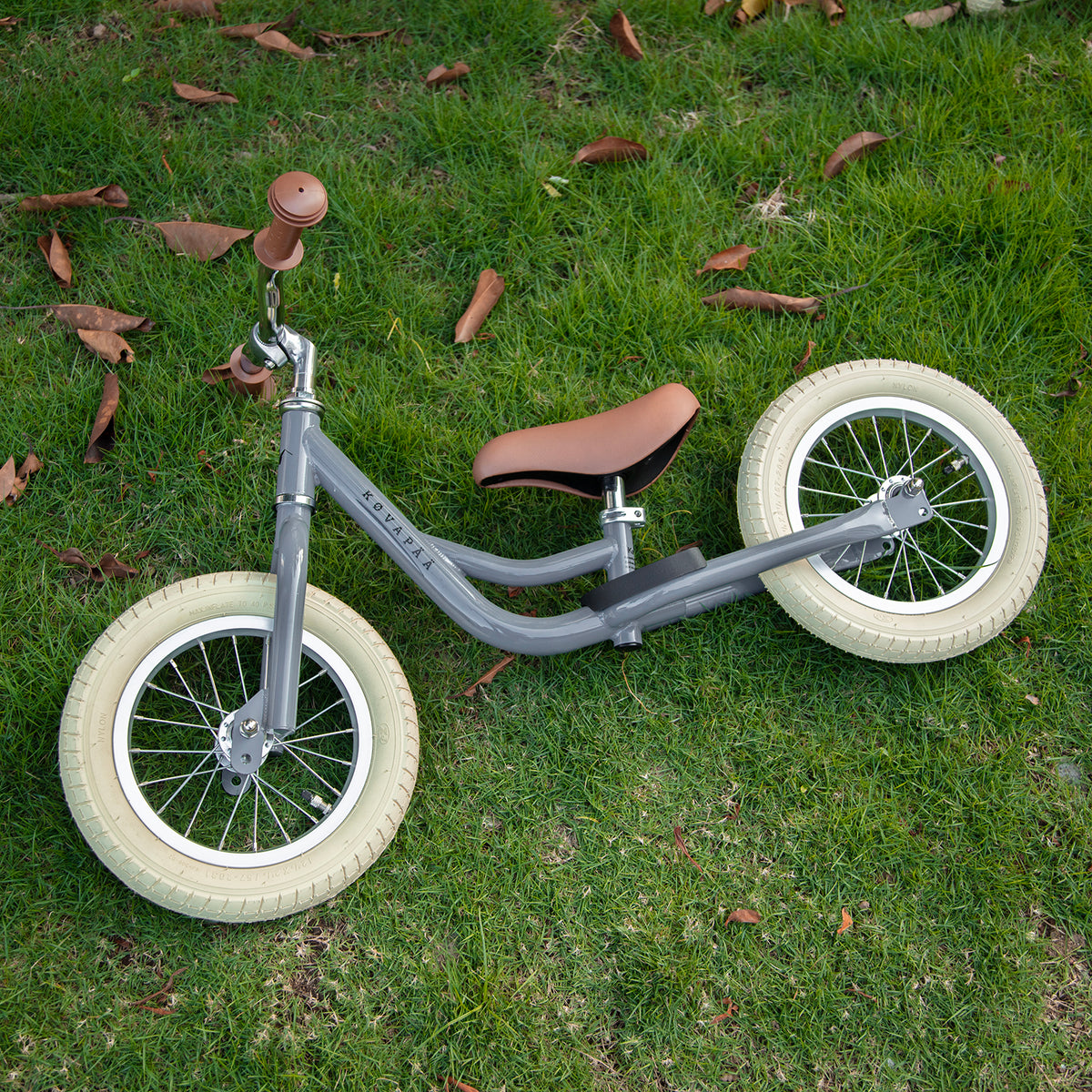 Køvapää grijze 2-in-1 loopfiets buiten in het gras gefotografeerd
