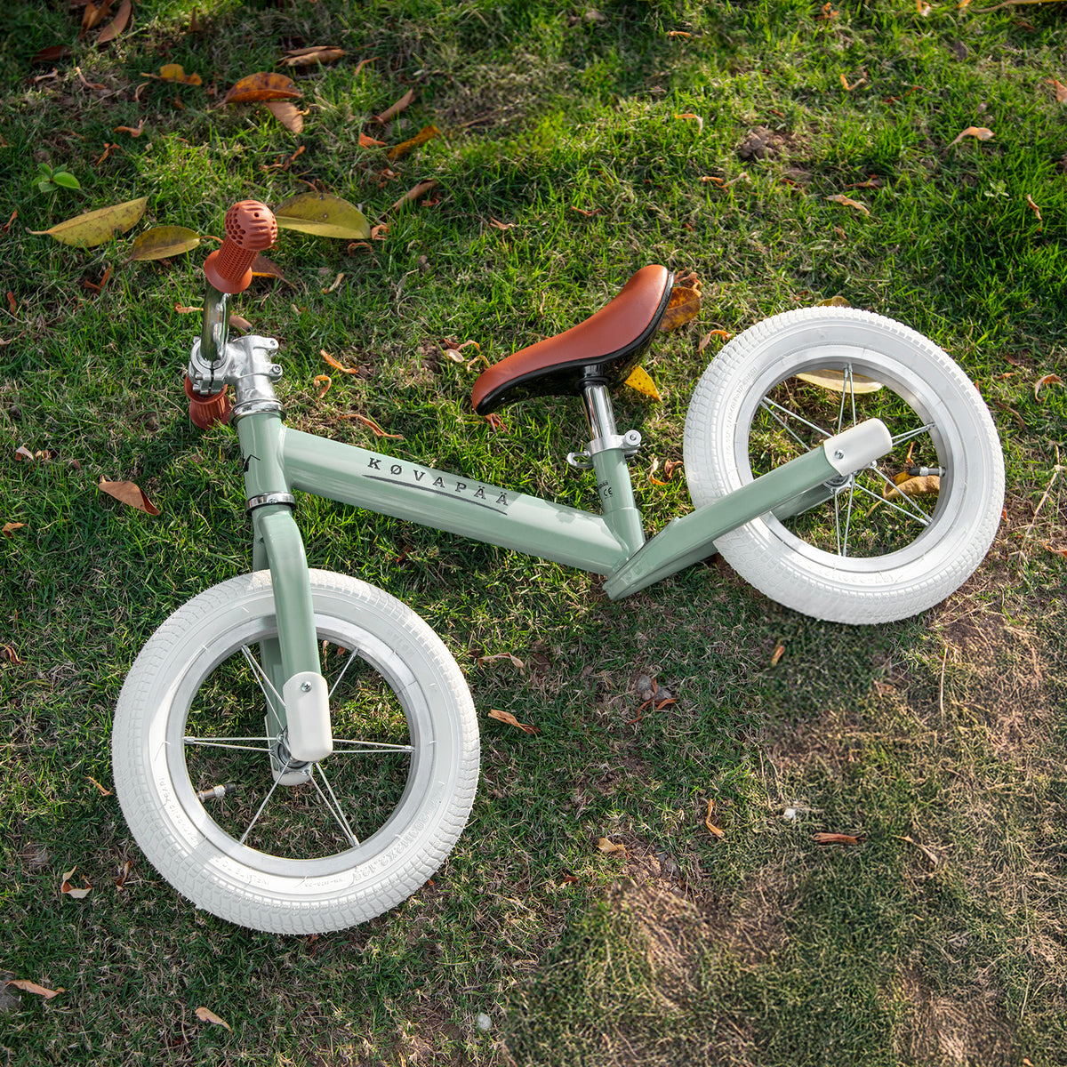 groene Køvapää loopfiets buiten in het gras gefotografeerd
